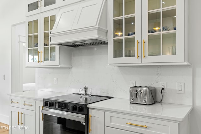 kitchen with white cabinets, stainless steel electric range oven, premium range hood, and tasteful backsplash