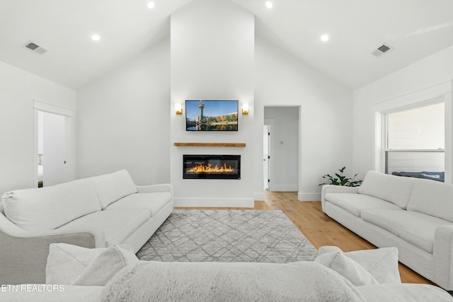 living room with high vaulted ceiling and light hardwood / wood-style flooring