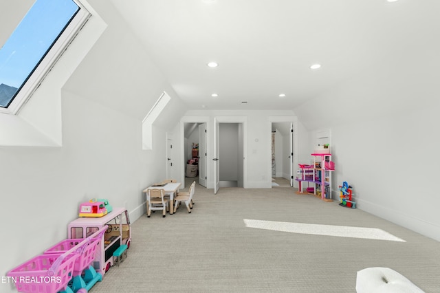 recreation room featuring light carpet and vaulted ceiling with skylight