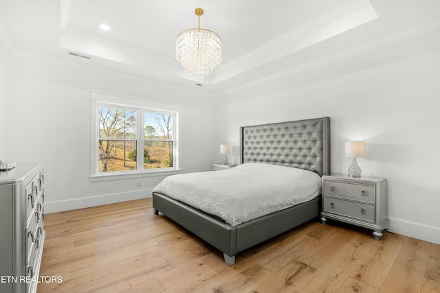 bedroom with a notable chandelier, light hardwood / wood-style floors, a raised ceiling, and ornamental molding