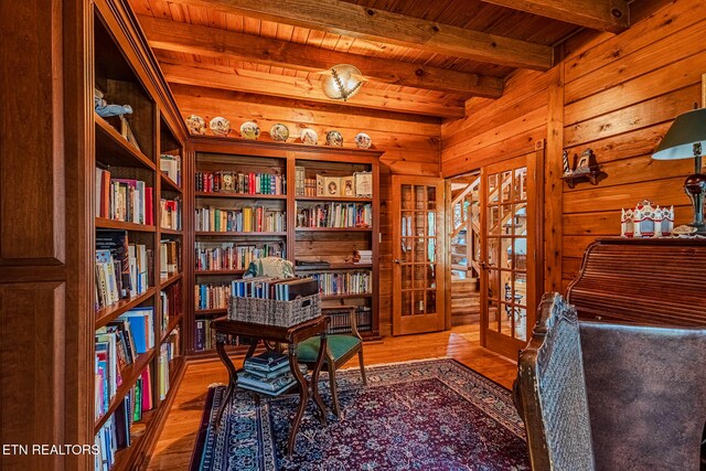 sitting room with wood walls, french doors, light wood-type flooring, beamed ceiling, and wood ceiling