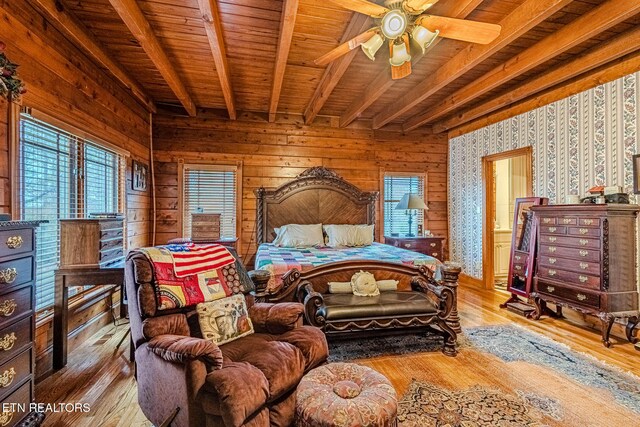 bedroom with beam ceiling, wood walls, ceiling fan, and hardwood / wood-style flooring