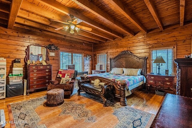 bedroom with hardwood / wood-style floors, multiple windows, and wooden walls