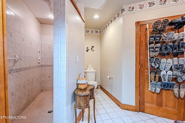 bathroom featuring toilet, a tile shower, and tile patterned floors