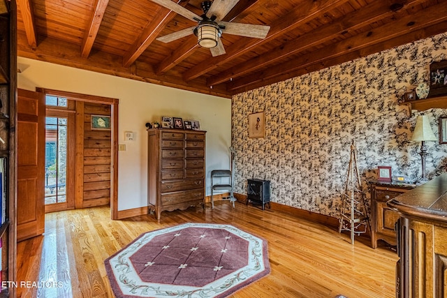 unfurnished living room with wood ceiling, ceiling fan, wood-type flooring, beamed ceiling, and a wood stove