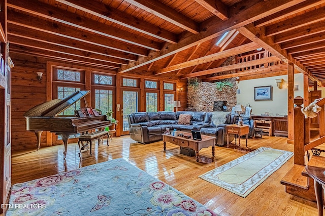 living room featuring light wood-type flooring, a large fireplace, wooden walls, beam ceiling, and wooden ceiling