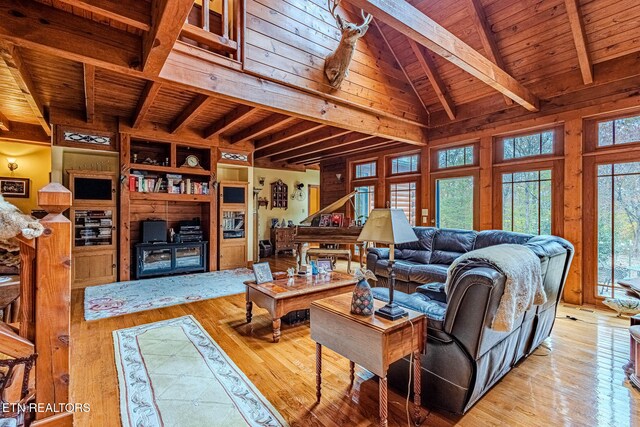 living room featuring lofted ceiling with beams, light hardwood / wood-style floors, wood walls, and wood ceiling