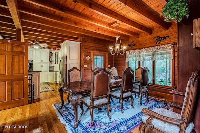 dining area featuring beam ceiling, light wood-type flooring, a healthy amount of sunlight, and a notable chandelier