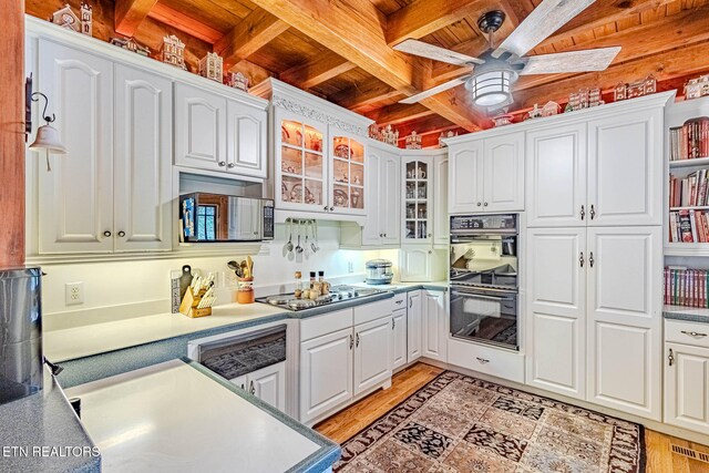 kitchen featuring beamed ceiling, white cabinets, stainless steel appliances, and light wood-type flooring