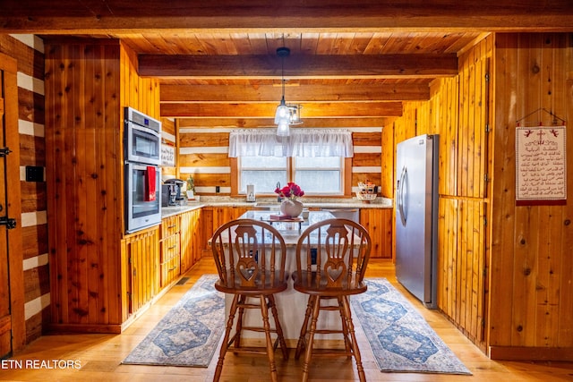 interior space featuring beam ceiling, wooden ceiling, wood walls, light hardwood / wood-style floors, and appliances with stainless steel finishes