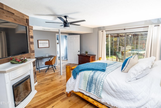 bedroom featuring access to exterior, a textured ceiling, light wood-type flooring, and ceiling fan