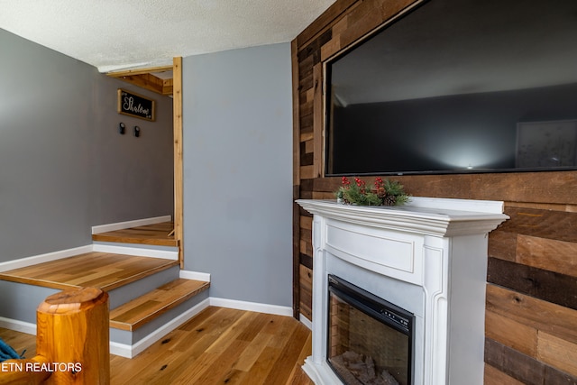 interior space with wood walls, light hardwood / wood-style floors, and a textured ceiling