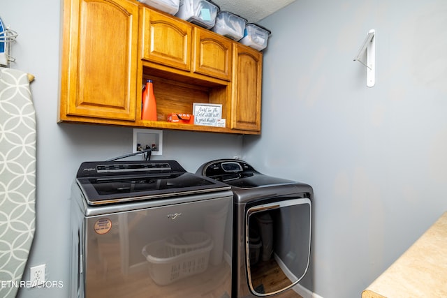 laundry room with cabinets, a textured ceiling, and washing machine and dryer