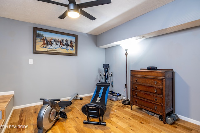 workout room featuring a textured ceiling, light hardwood / wood-style floors, and ceiling fan