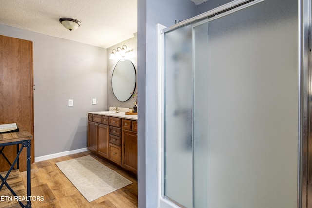 bathroom with hardwood / wood-style floors, vanity, a textured ceiling, and an enclosed shower