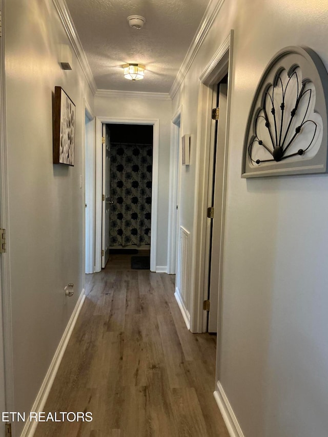 corridor featuring hardwood / wood-style floors, crown molding, and a textured ceiling