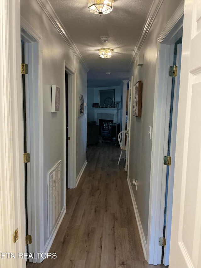 hallway featuring hardwood / wood-style floors, a textured ceiling, and crown molding