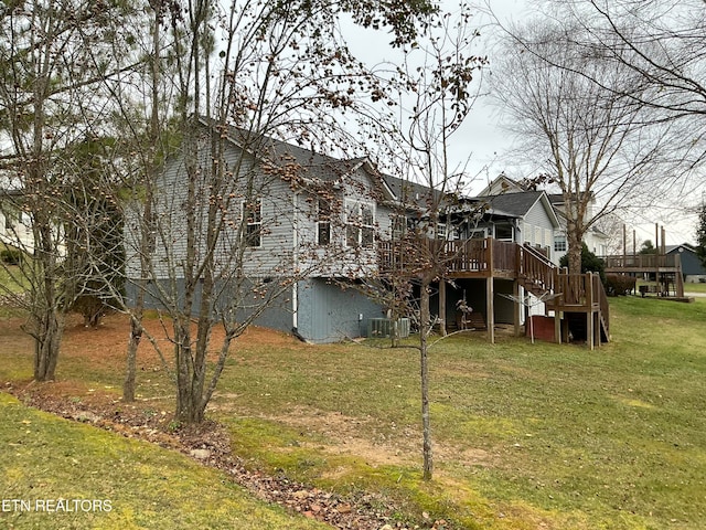 rear view of property featuring a yard and a wooden deck