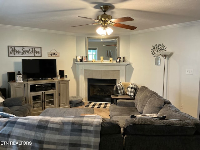 living room featuring ceiling fan, crown molding, and a fireplace