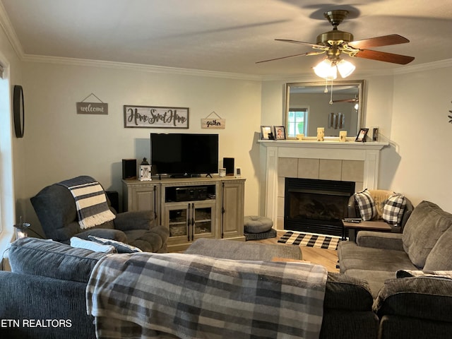 living room with a tile fireplace, hardwood / wood-style flooring, ceiling fan, and ornamental molding