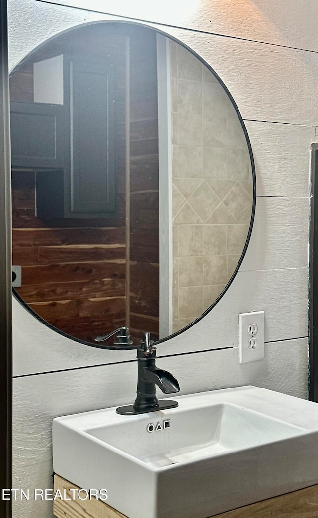 bathroom featuring wooden walls and sink