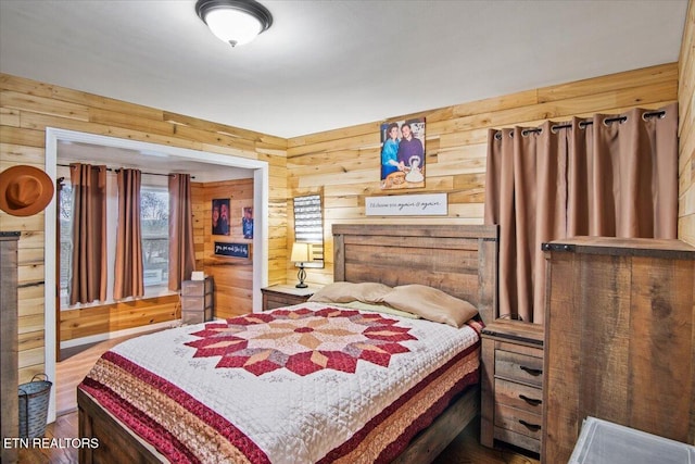 bedroom with hardwood / wood-style floors and wooden walls