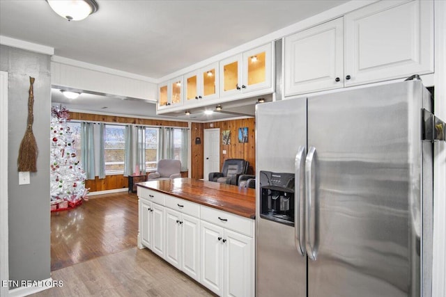 kitchen featuring white cabinetry, wood walls, and stainless steel refrigerator with ice dispenser