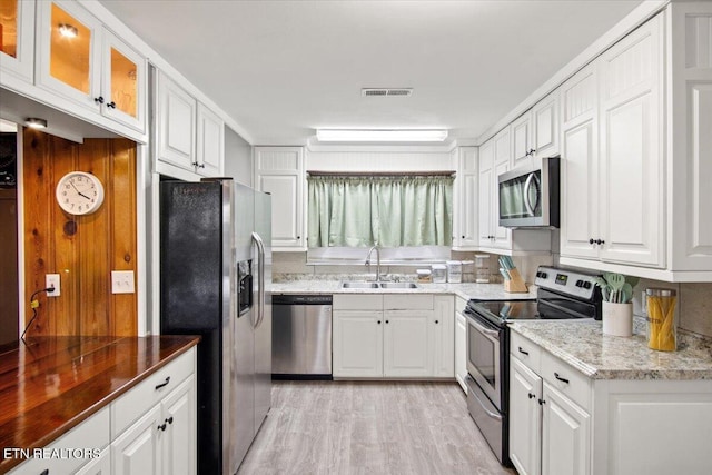 kitchen with white cabinets, light hardwood / wood-style floors, sink, and appliances with stainless steel finishes