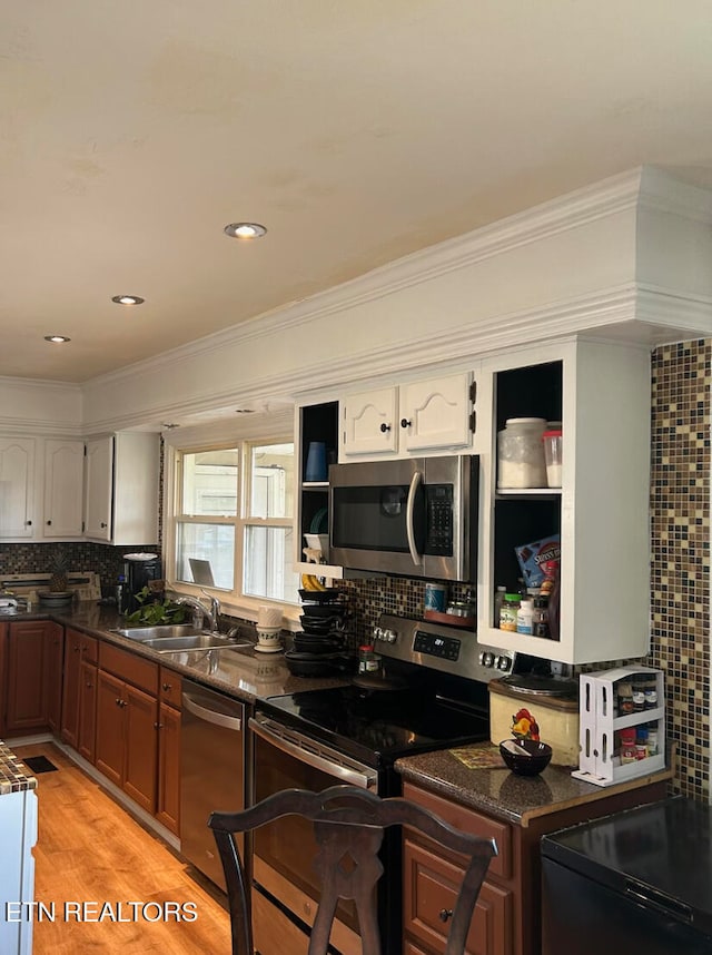 kitchen with crown molding, sink, tasteful backsplash, white cabinetry, and stainless steel appliances