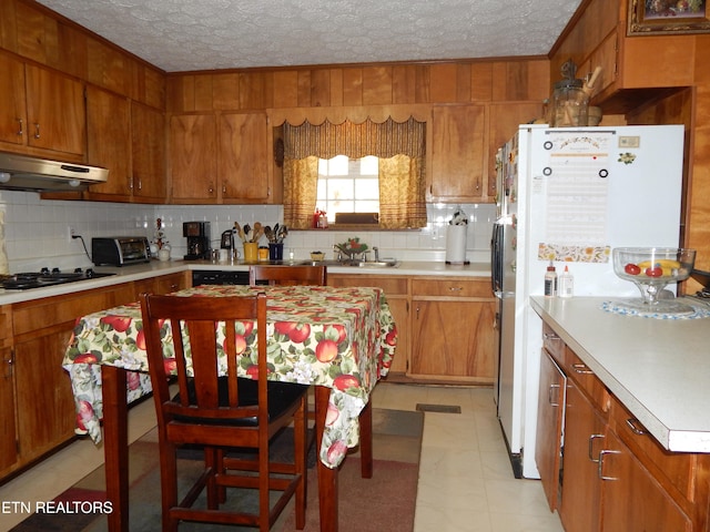 kitchen featuring tasteful backsplash, light tile patterned floors, white fridge, and a textured ceiling