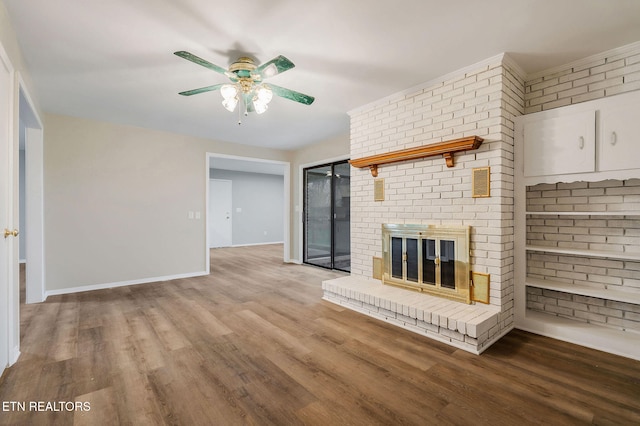 unfurnished living room featuring ceiling fan, a fireplace, wood-type flooring, and brick wall