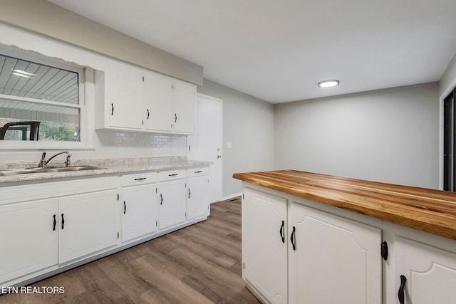 kitchen with decorative backsplash, sink, butcher block countertops, white cabinets, and light hardwood / wood-style floors