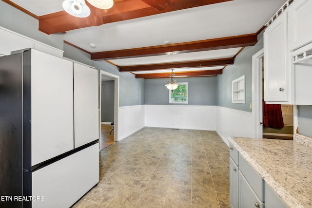 kitchen with light stone countertops, beam ceiling, decorative light fixtures, white fridge, and white cabinetry