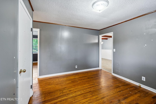 empty room with a textured ceiling, crown molding, and dark hardwood / wood-style floors