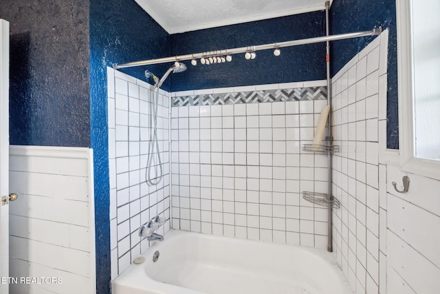 bathroom with a textured ceiling and tiled shower / bath