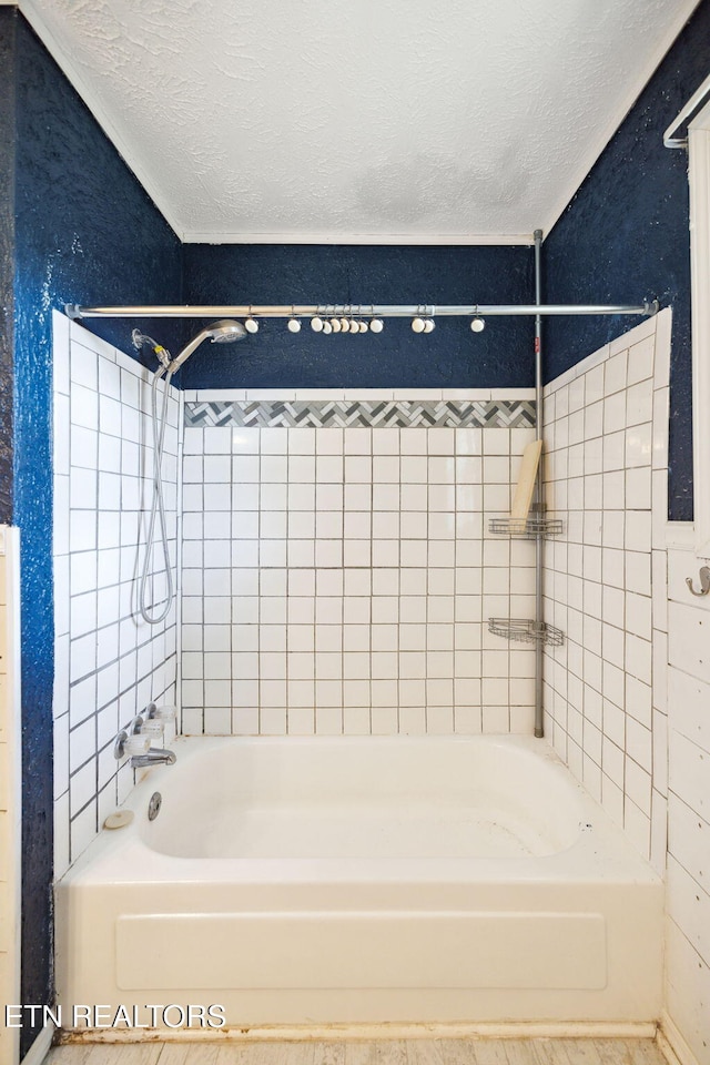 bathroom featuring a textured ceiling and tiled shower / bath