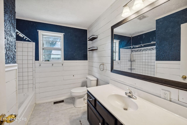 full bathroom featuring tiled shower / bath combo, tile patterned floors, toilet, wooden walls, and vanity