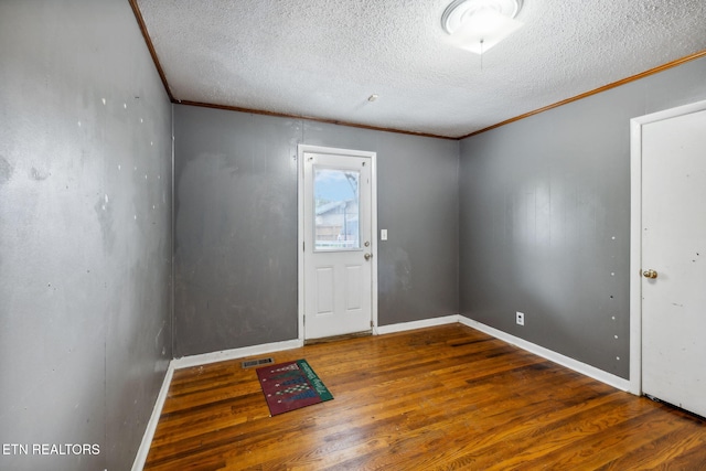 foyer entrance with a textured ceiling, crown molding, and dark wood-type flooring