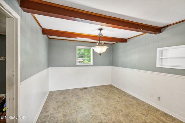 spare room featuring beam ceiling and wood walls