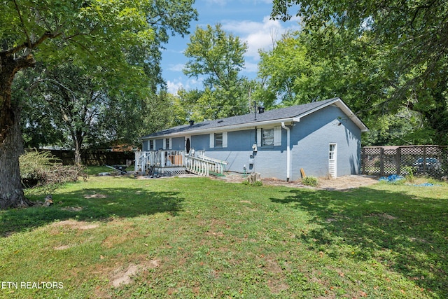 rear view of property with a wooden deck and a yard