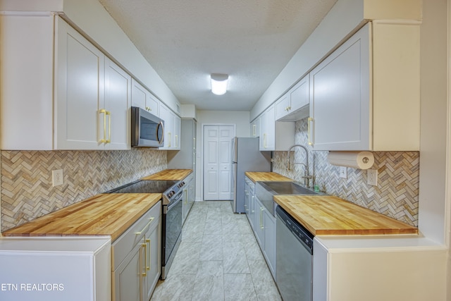 kitchen featuring white cabinetry, butcher block counters, sink, and appliances with stainless steel finishes