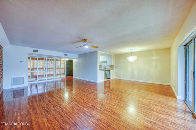 unfurnished living room with ceiling fan with notable chandelier, a textured ceiling, light hardwood / wood-style flooring, and sink