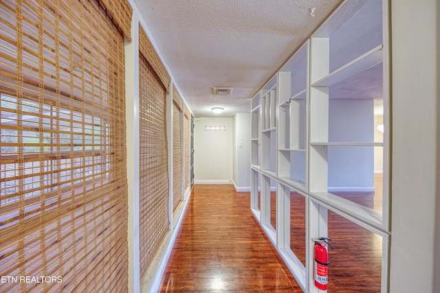 corridor with hardwood / wood-style floors and a textured ceiling