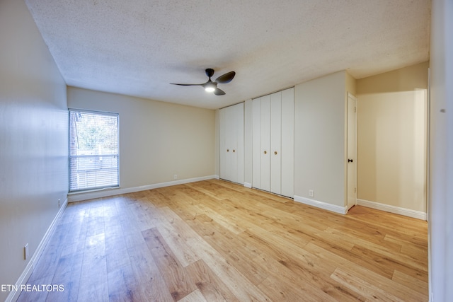 unfurnished bedroom featuring ceiling fan, light hardwood / wood-style floors, and a textured ceiling