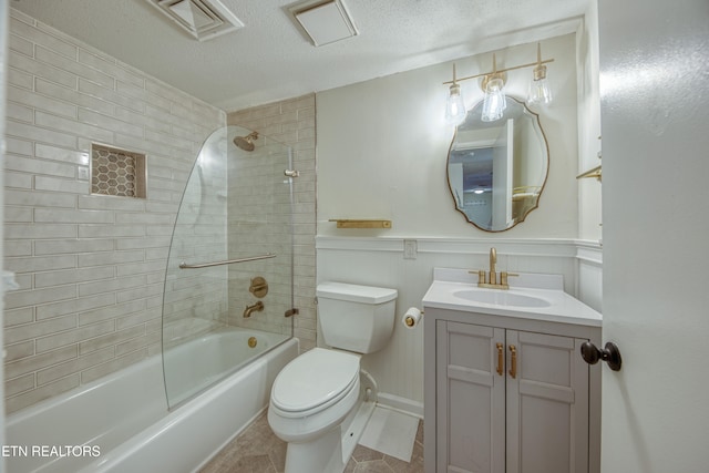 full bathroom featuring tiled shower / bath combo, tile patterned floors, a textured ceiling, toilet, and vanity