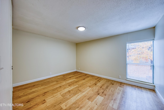 spare room featuring a textured ceiling and light wood-type flooring