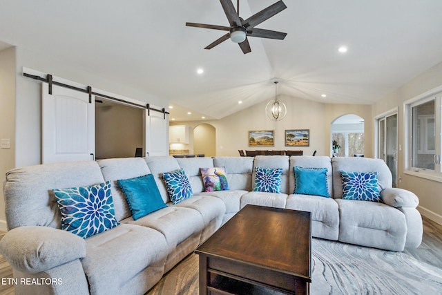 living room featuring a barn door, light hardwood / wood-style flooring, vaulted ceiling, and ceiling fan