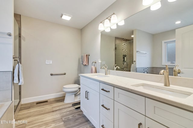 bathroom featuring hardwood / wood-style floors, vanity, toilet, and an enclosed shower