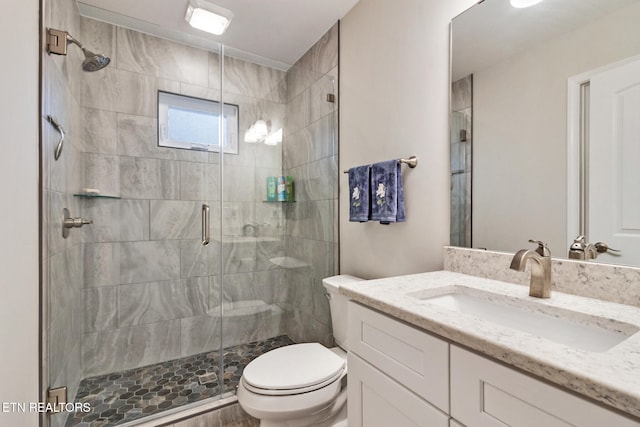 bathroom featuring an enclosed shower, vanity, and toilet