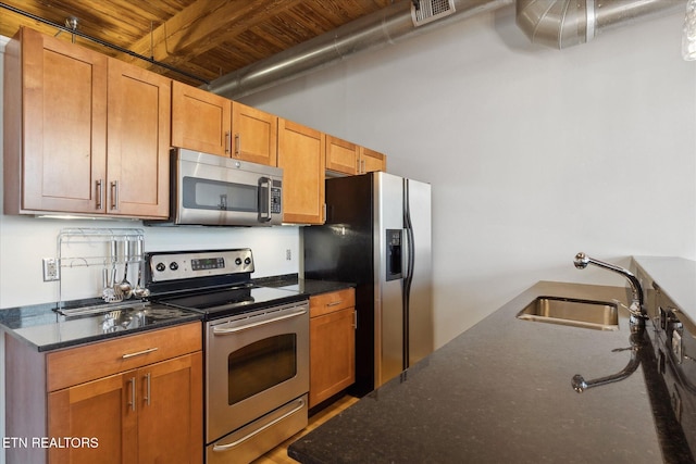 kitchen with appliances with stainless steel finishes, dark stone countertops, wooden ceiling, and sink